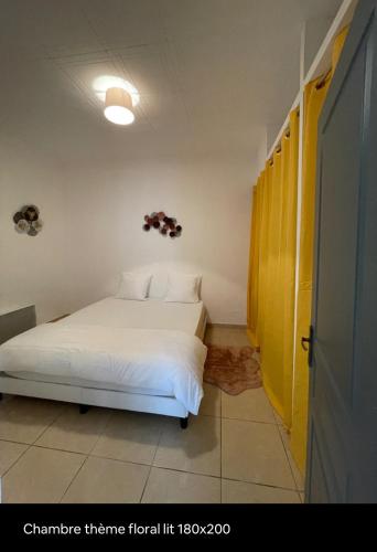 - une chambre avec un lit blanc et une porte jaune dans l'établissement Villa agréable, à Villedaigne