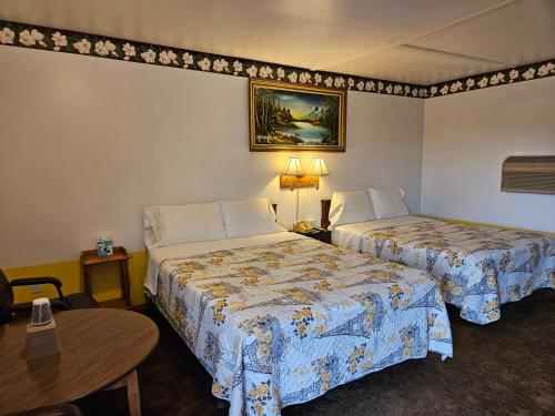a hotel room with two beds and a table at American Inn Motel Canon City in Canon City