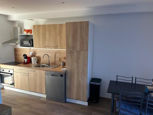 une cuisine avec des armoires en bois, un évier et une table dans l'établissement Magnifique appartement en bord de mer, à Borgo