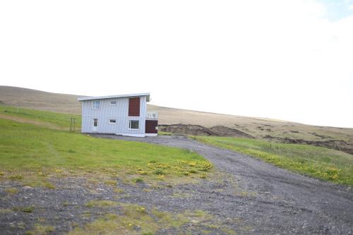 a small white house on a hill with a dirt road at Hekla Adventures in Hvolsvöllur