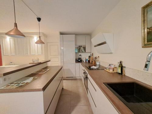 une grande cuisine avec des placards blancs et un évier dans l'établissement Salle - CI - Appartement avec jardin - Paris 6ème, à Paris