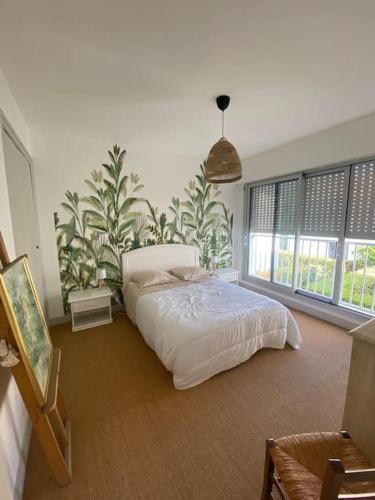 une chambre avec un lit dans une pièce avec des fenêtres dans l'établissement Maison bord de mer 50 M, à Saint-Georges-de-Didonne