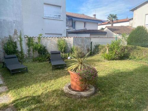 une cour avec deux chaises et une plante en pot dans l'établissement Maison bord de mer 50 M, à Saint-Georges-de-Didonne