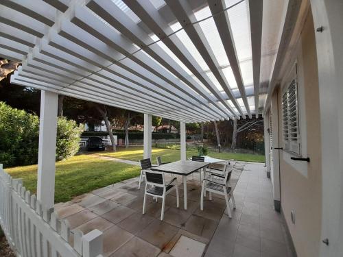 a white pergola on a patio with a table and chairs at Casa Mac in La Ciaccia