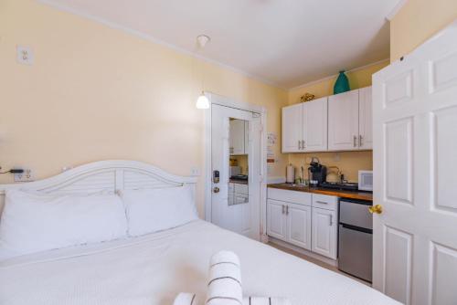 a white bedroom with a white bed and a kitchen at Andy's Attic in Key West
