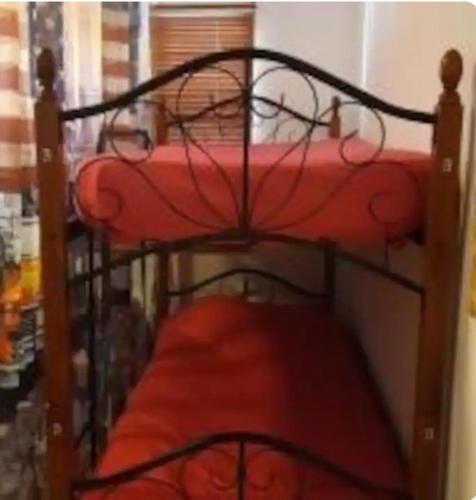 a bunk bed with red sheets and a red mattress at FIRST DAY HOSTEL on ARUBA in Oranjestad
