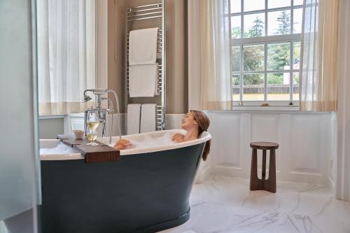 a woman sitting in a bath tub in a bathroom at Casa Velha do Palheiro Relais & Chateaux in Funchal