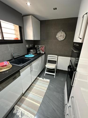 a kitchen with white cabinets and a sink and a chair at Duplex Pieds dans L'eau in Douar el Hafey