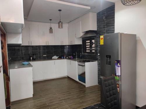 a kitchen with white cabinets and a stainless steel refrigerator at Villa ORMACE in Lomé