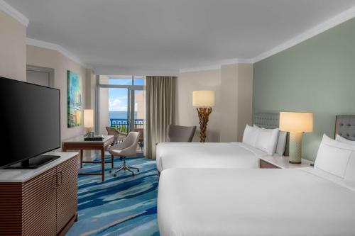 a hotel room with two beds and a flat screen tv at Hilton Aruba Caribbean Resort & Casino in Palm-Eagle Beach
