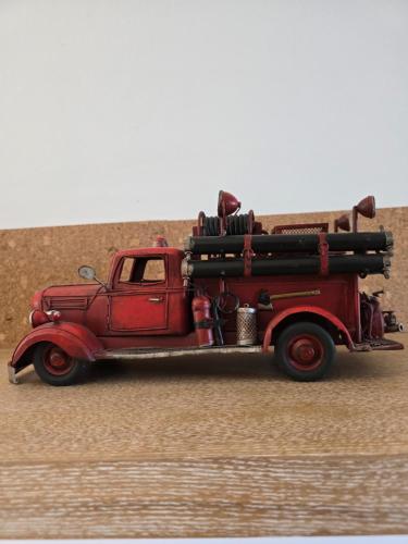 an old red fire truck driving down a road at Hôtel L'ideal le Mountbatten in Arromanches-les-Bains