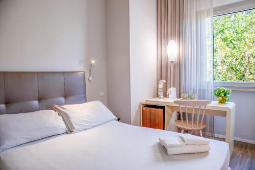 a bedroom with a bed and a desk and a window at Hotel De La Ville depandance di Hotel Augustus in Fano