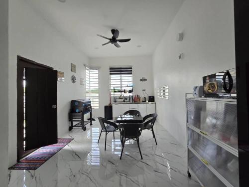 un soggiorno con tavolo e ventilatore a soffitto di The Bangau Cottage a Sungai Petani