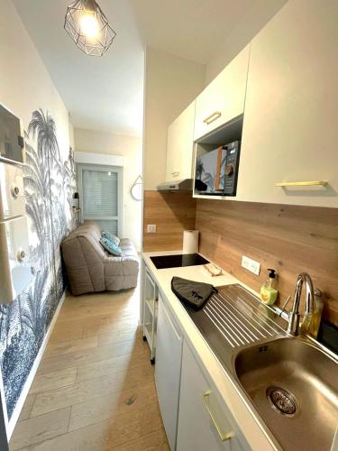 une cuisine avec un évier et un canapé dans une chambre dans l'établissement Studio Chic & Balcon - Hypercentre - Gare - Metro, à Toulouse