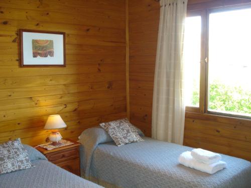 a bedroom with two twin beds and a window at Hosteria Rukahué in El Calafate