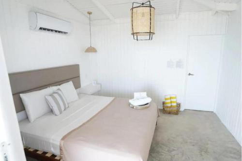 Trujillo AltoにあるVilla Familiar frente al mar Puerto Ricoの白いベッドルーム(大型ベッド1台、シャンデリア付)