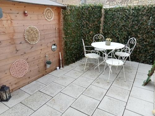 a patio with a table and chairs and a fence at Charmant petit logement in Bayeux