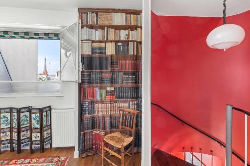 une chambre avec un mur rouge et une bibliothèque remplie de livres dans l'établissement paris invalides vue Tour Eiffel duplex, à Paris