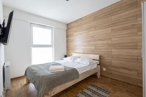 a bedroom with a bed with a wooden wall at VIP Apartamenty Wieniawskiego in Rzeszów