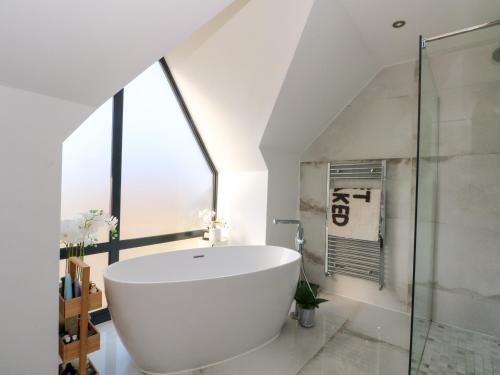 a bathroom with a large white tub and a glass shower at Rye Croft in Neston