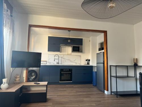 une grande cuisine avec des placards bleus et une télévision dans l'établissement Elisabeth, à Bray-Dunes