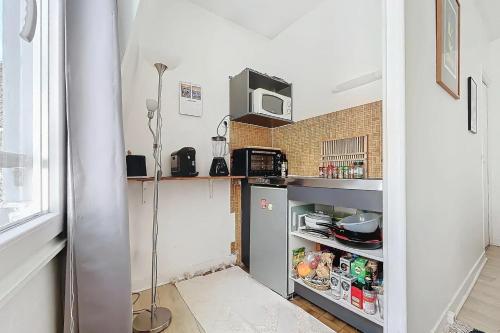 une petite cuisine avec un réfrigérateur et un micro-ondes dans l'établissement Cozy Studio in the Heart of Oberkampf, à Paris