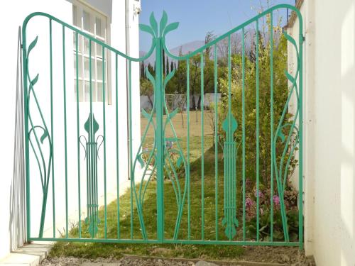 a green metal gate with a garden behind it at Casa Deco Hotel Boutique in Cochabamba