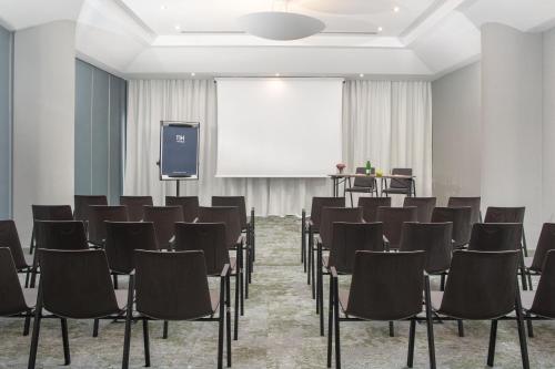 a conference room with chairs and a screen at NH Catania Centro in Catania