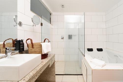 a white bathroom with a sink and a tub at Pousada Pedra da Ilha in Penha