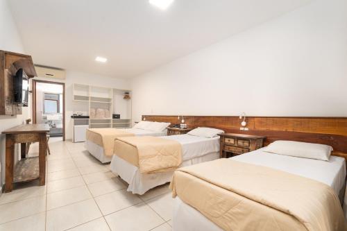 a hotel room with four beds and a kitchen at Pousada Pedra da Ilha in Penha