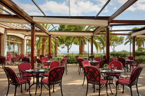 a row of tables and chairs with red chairs at Castillo Hotel Son Vida, a Luxury Collection Hotel, Mallorca in Palma de Mallorca