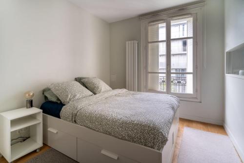 une chambre blanche avec un lit et une fenêtre dans l'établissement Airy and Stylish 1BD Flat ile Saint-Louis, à Paris