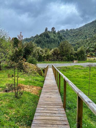 a wooden bridge over a field with a river at Hotel Neyün La Junta in La Junta