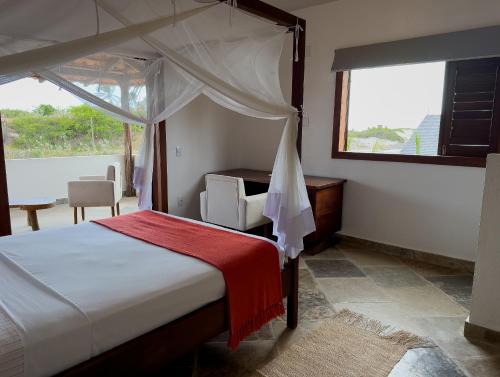 a bedroom with a bed and a desk and a window at Exclusive House Preá in Cruz