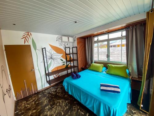 a bedroom with a blue bed with a painting on the wall at Villa Mitirapa in Tohautu