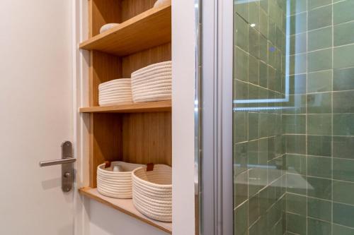 une armoire remplie d'assiettes et de vaisselle dans la salle de bains dans l'établissement Airy and Stylish 1BD Flat ile Saint-Louis, à Paris