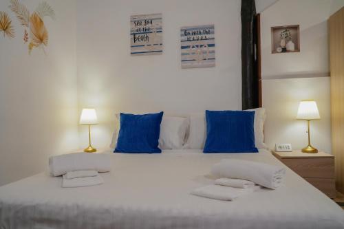 a large white bed with blue pillows and two lamps at R-HOME Li Cuti in Catania
