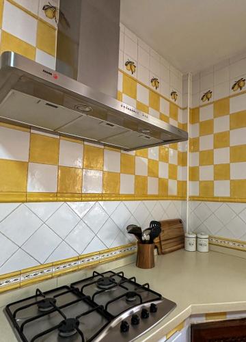 a stove top in a kitchen with yellow and white tiles at Casa Rural El Pomelo in Zurgena