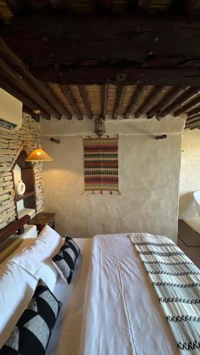a bedroom with a white bed with a rug on the wall at نزل حارة المسفاة Harit AL Misfah Inn in Misfāh