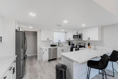 a white kitchen with white cabinets and a refrigerator at 5Mins to Fremont 10Mins to Strip! Sleeps 8! in Las Vegas