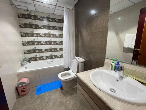 a bathroom with a sink and a toilet and a tub at The Sea Facing Apartment in Ajman 
