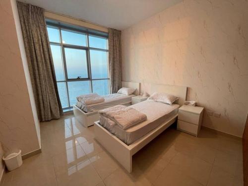 a bedroom with two beds and a large window at The Sea Facing Apartment in Ajman 
