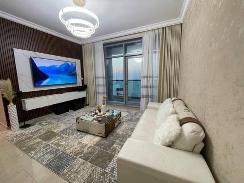 a living room with a white couch and a flat screen tv at The Sea Facing Apartment in Ajman