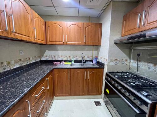 a kitchen with wooden cabinets and a sink and a stove at The Sea Facing Apartment in Ajman