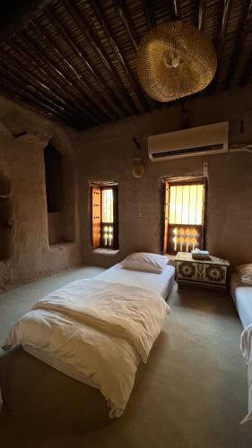 a bedroom with two beds and a table and two windows at نزل حارة المسفاة Harit AL Misfah Inn in Misfāh