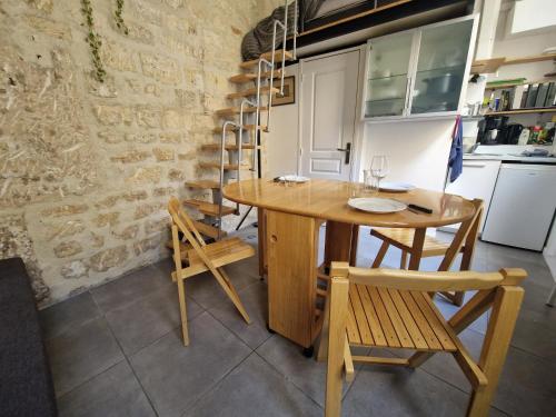 une salle à manger avec une table et des chaises en bois dans l'établissement Studio Marais Ménilmontant, à Paris