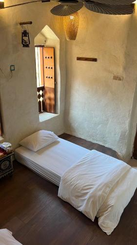 a white bed in a room with a window at نزل حارة المسفاة Harit AL Misfah Inn in Misfāh