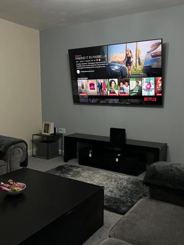 a living room with a flat screen tv on the wall at Cosy 2 Bed Service Apartment Netflix Hideaway Family Couples Staycation Tredegar Park Celtic Manor ICC Wales in Lower Clapton