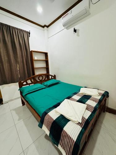 a bedroom with a bed with a green comforter at Avanthika Holiday INN in Jaffna