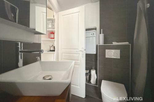 La salle de bains est pourvue d'un lavabo blanc et d'un réfrigérateur. dans l'établissement Flexliving - One bedroom - Croix Nivert, à Paris